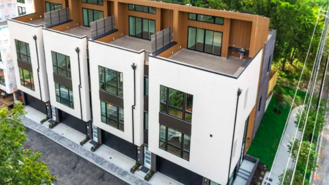 An aerial photo of a large white and brown townhome project in Atlanta near a wide street and trees.