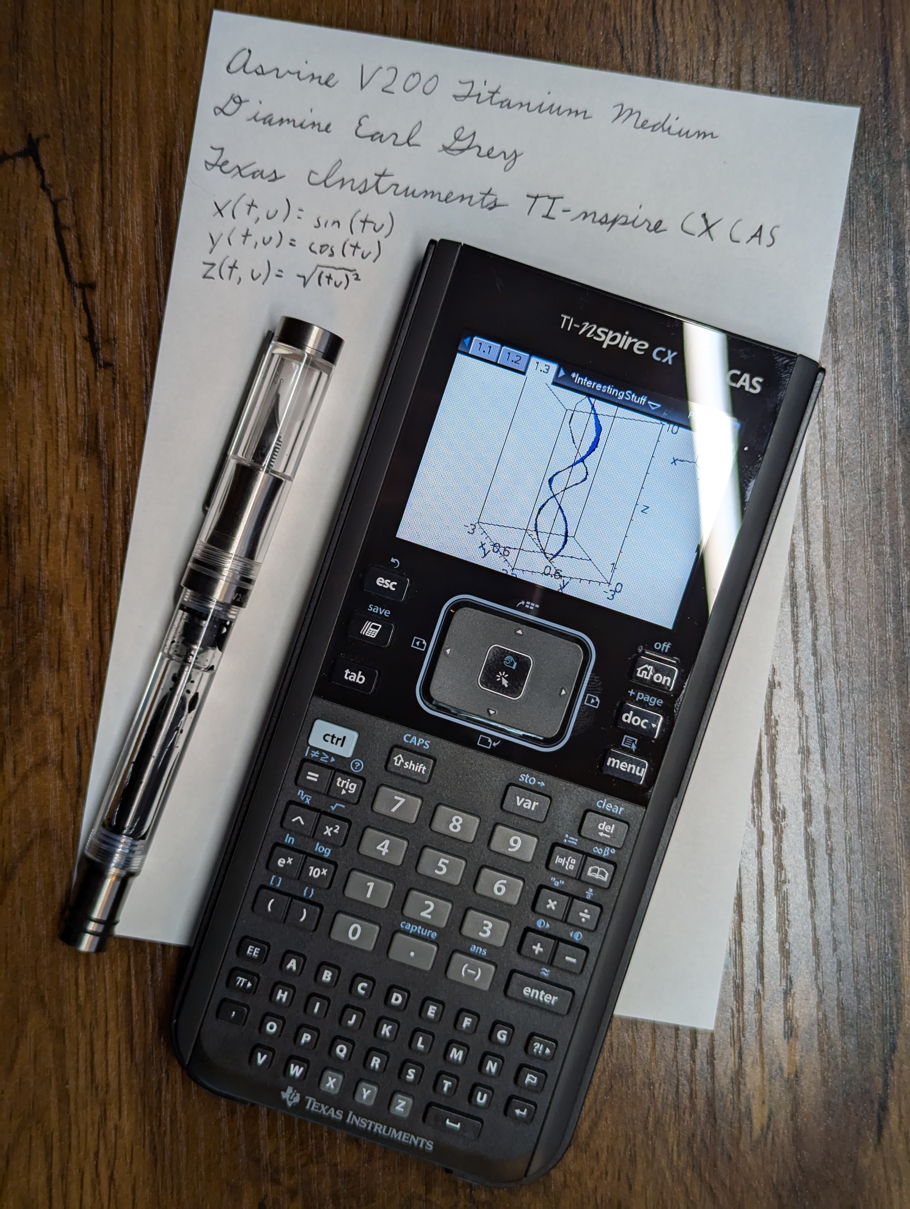 Asvine V200 Titanium fountain pen next to a TI-nspire CX CAS calculator.  Both are on a shit of paper with the description of the items and the equation displayed on the calculator written out.