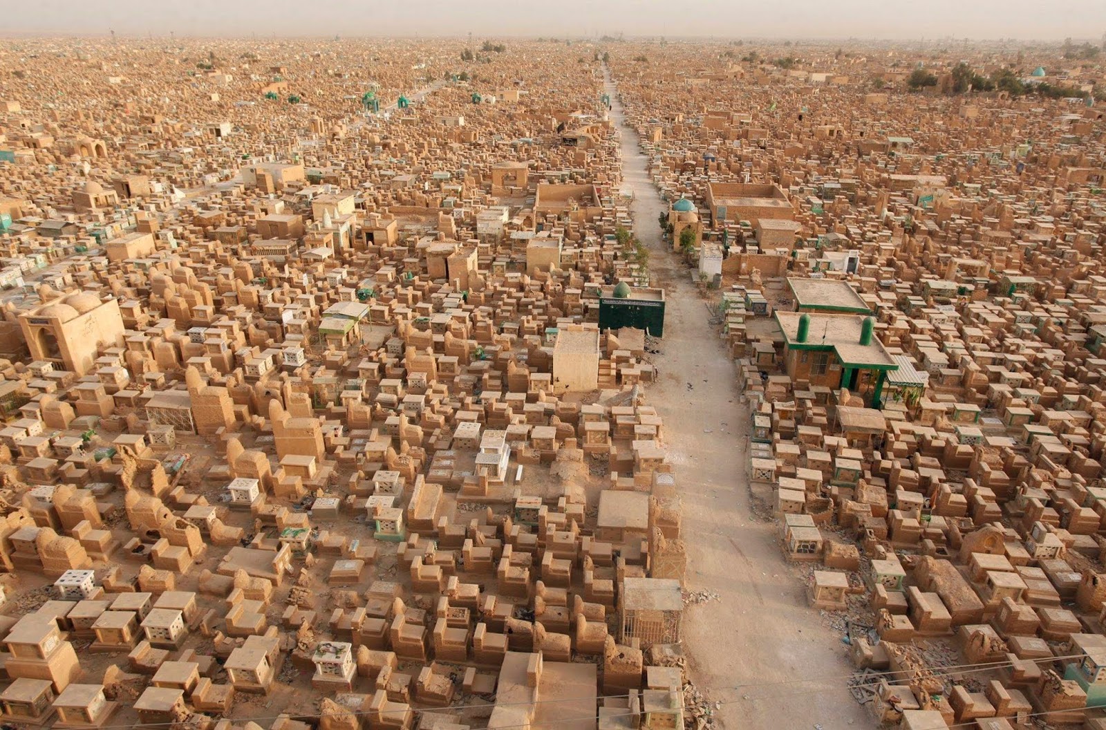 picture of wadi al-salaam graveyard picturing hundreds of above ground tombs, mostly only large enough for a single person's body. There is a path through the tombs receding into the distance