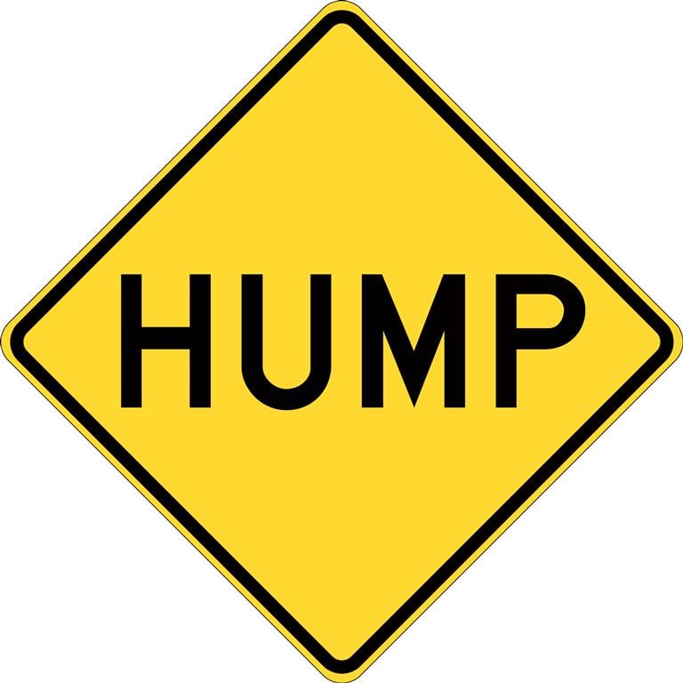 caution yellow road sign with the word “hump” on it